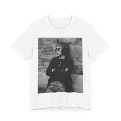 A black graphic t-shirt featuring a vintage graphic related to Elton John's 'Farewell Yellow Brick Road' tour.