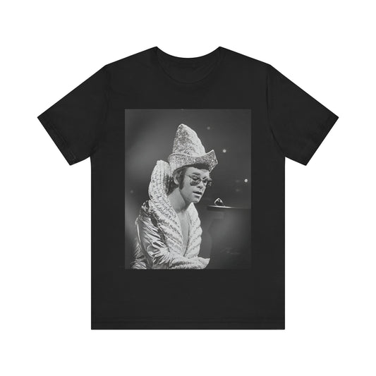 A black graphic t-shirt featuring a 70s pop aesthetic graphic of Elton John.