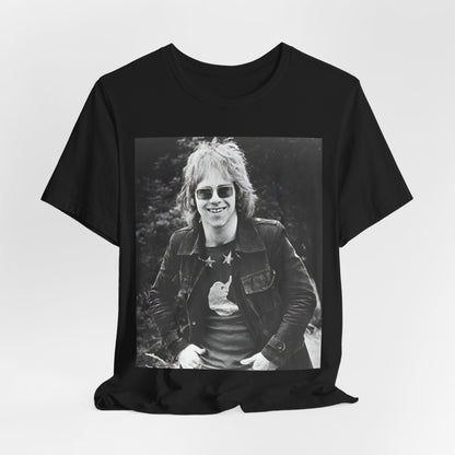 A black graphic t-shirt featuring a 70s black and white monochrome graphic or photo of Elton John.