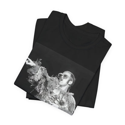 A black graphic t-shirt featuring a retro graphic of Elton John as a rock legend performing live.