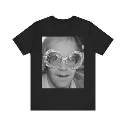 A black graphic t-shirt featuring a graphic of Elton John emphasizing his iconic glasses and fashion.