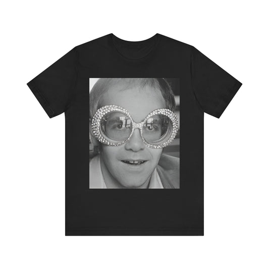 A black graphic t-shirt featuring a graphic of Elton John emphasizing his iconic glasses and fashion.
