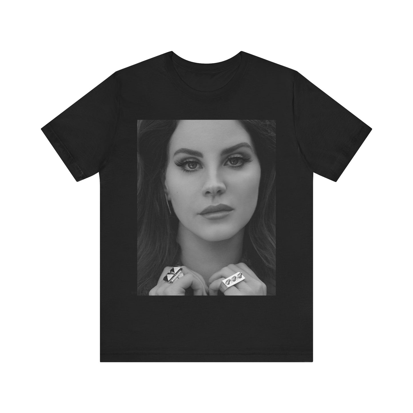 Black and white close-up portrait of Lana Del Rey with an intense gaze, her hands framing her face and showcasing large statement rings, printed on a graphic tee.
