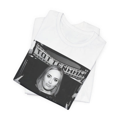 A black graphic t-shirt featuring a photo of Adele in a casual setting, surrounded by fans at a Tottenham event, showing her smiling or interacting.