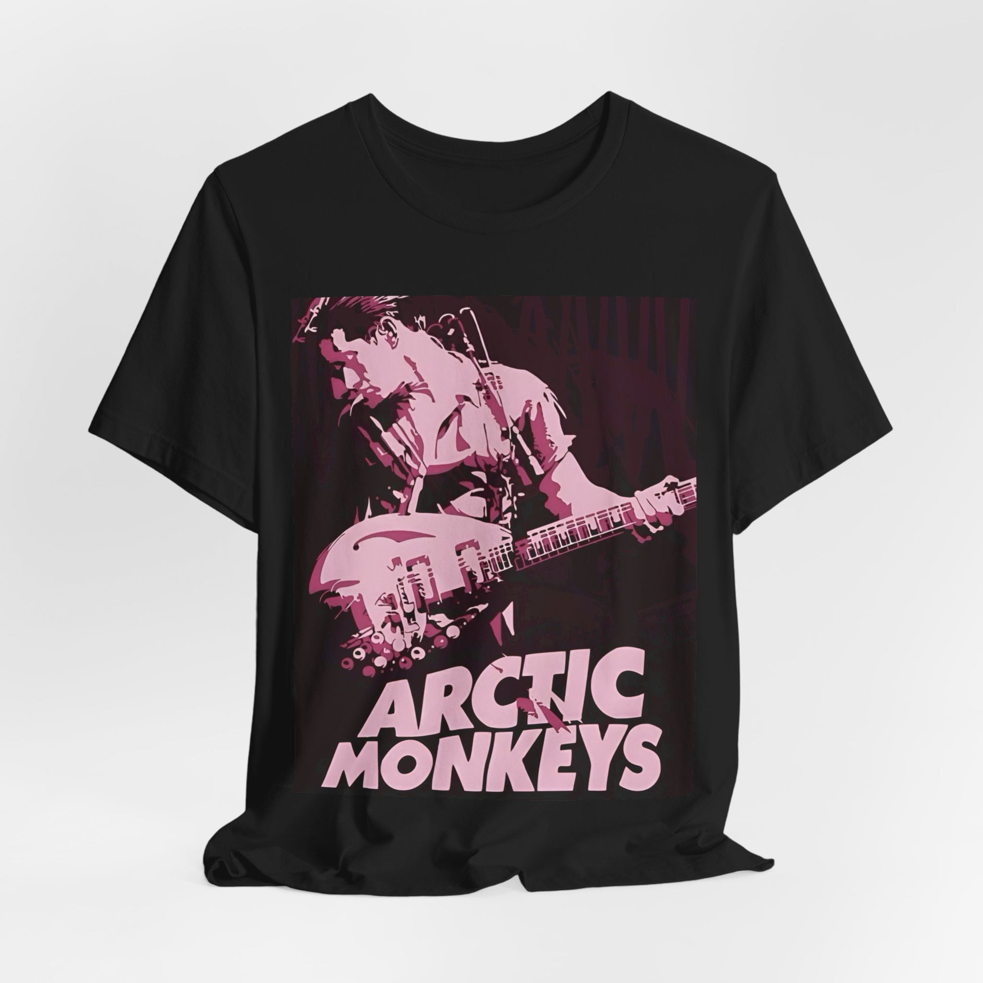 A black graphic t-shirt featuring the Arctic Monkeys logo in a prominent pink color, creating an aesthetic look.
