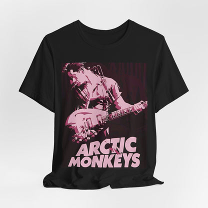 A black graphic t-shirt featuring the Arctic Monkeys logo in a prominent pink color, creating an aesthetic look.