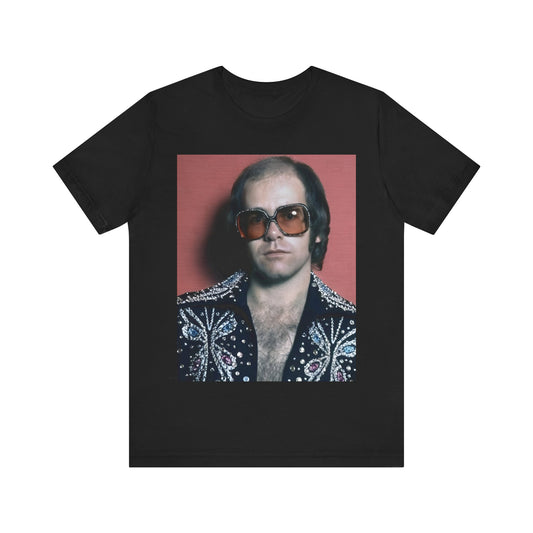 A black graphic t-shirt featuring a vintage glam rock icon graphic of Elton John.