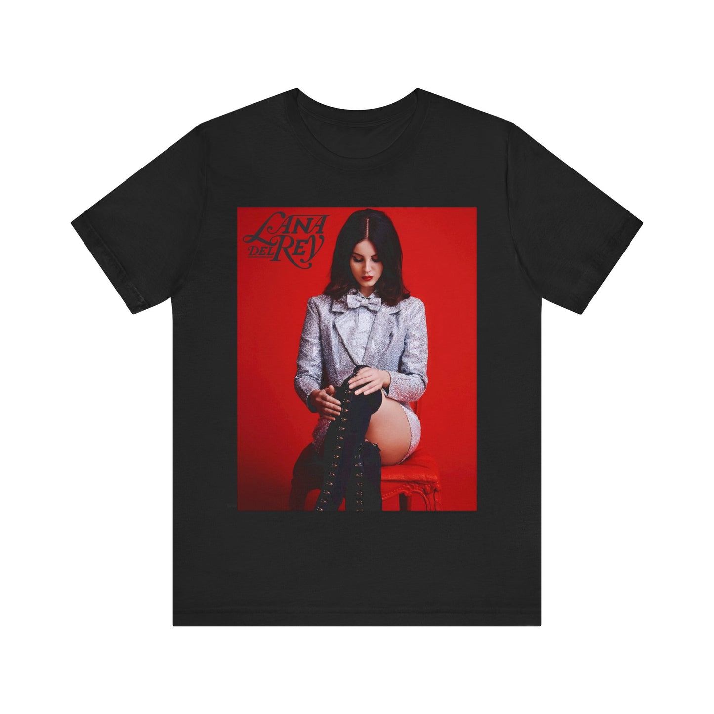 Lana Del Rey sitting in a red chair, wearing a silver sequin jacket and lacing up a tall black boot, printed on a graphic t-shirt.