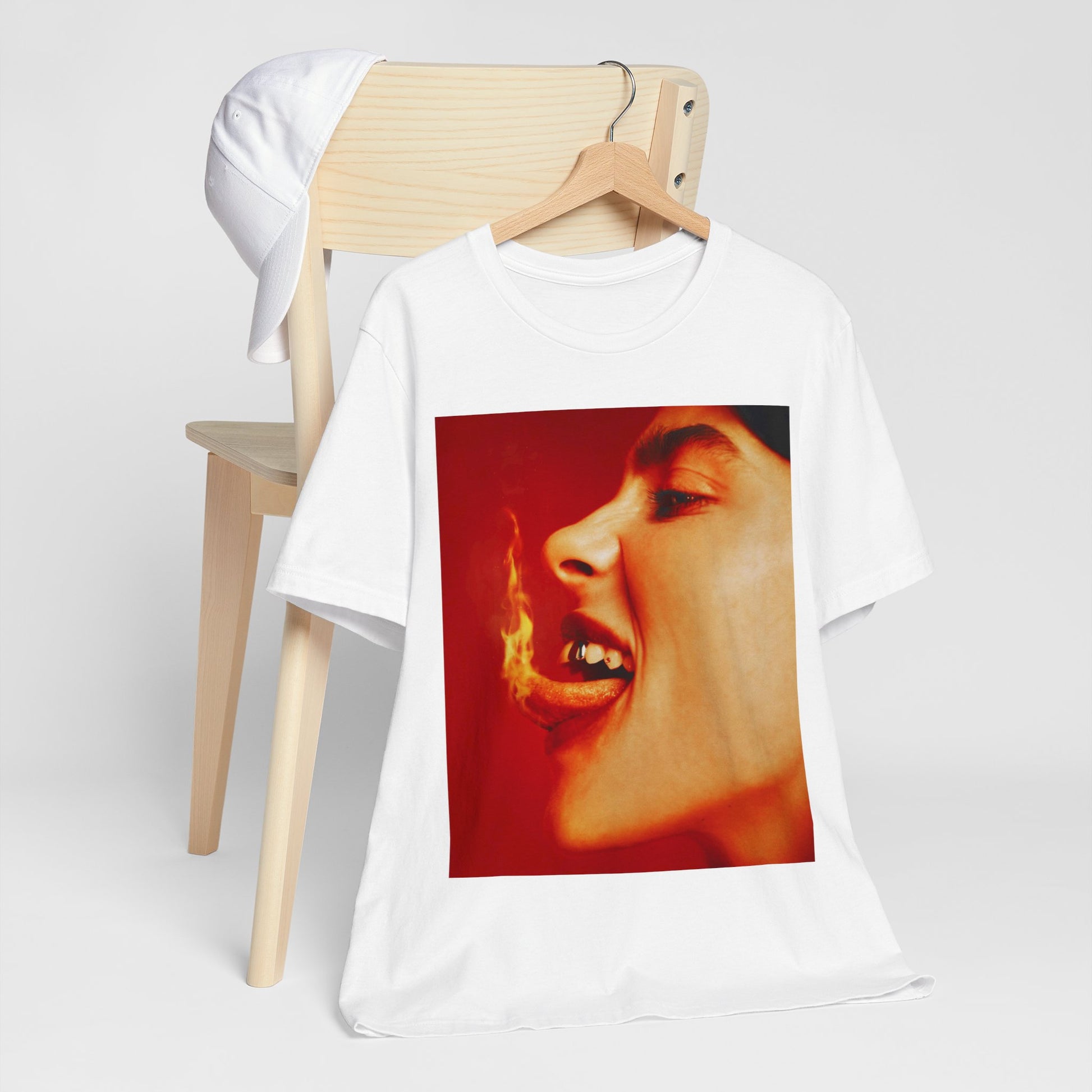 A close-up, red-toned photo of a face in profile with its mouth open and a live flame on the tongue, printed on a graphic t-shirt.