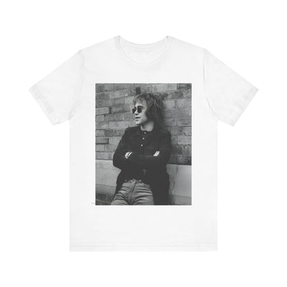 A black graphic t-shirt featuring a vintage graphic related to Elton John's 'Farewell Yellow Brick Road' tour.