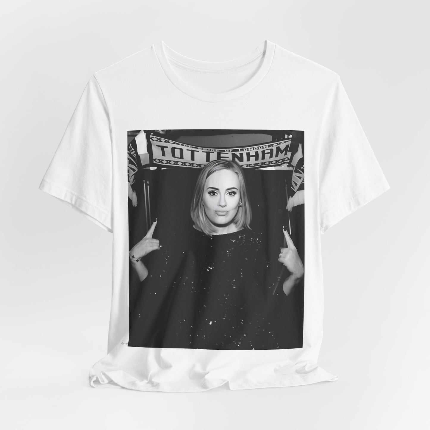 A black graphic t-shirt featuring a photo of Adele in a casual setting, surrounded by fans at a Tottenham event, showing her smiling or interacting.