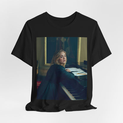 A black graphic t-shirt featuring a black and white photo of Adele sitting at a piano, with a focused and emotional expression as if performing.