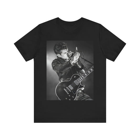 A black graphic t-shirt featuring a dynamic black and white graphic or photo of Arctic Monkeys performing live, emphasizing energy.