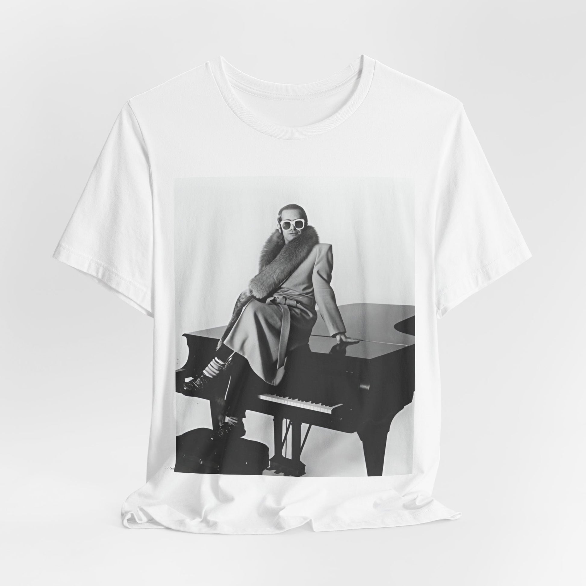 A black graphic t-shirt featuring a black and white photo of Elton John playing the piano.